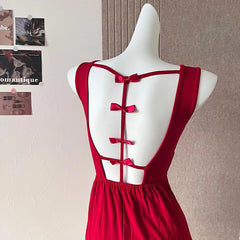 Red dress with open back on a mannequin against a neutral wall.