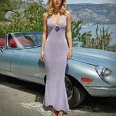 Woman in a long purple dress standing next to a vintage car with a scenic background