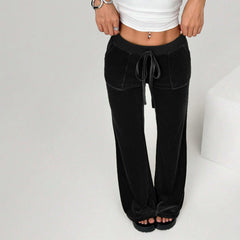 Person wearing black wide-leg pants and a white top on a light gray background