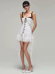 Woman wearing a white dress with black lace details on a gray background