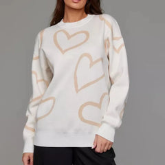 White sweater with beige heart patterns worn by a person