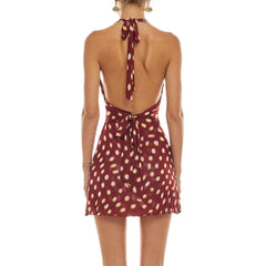 Woman wearing a burgundy dress with gold polka dots on a white background