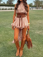 Woman in a pink dress with brown belt and boots standing on grass