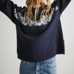 Navy sweater with white lace detailing worn by a person on a light gray background