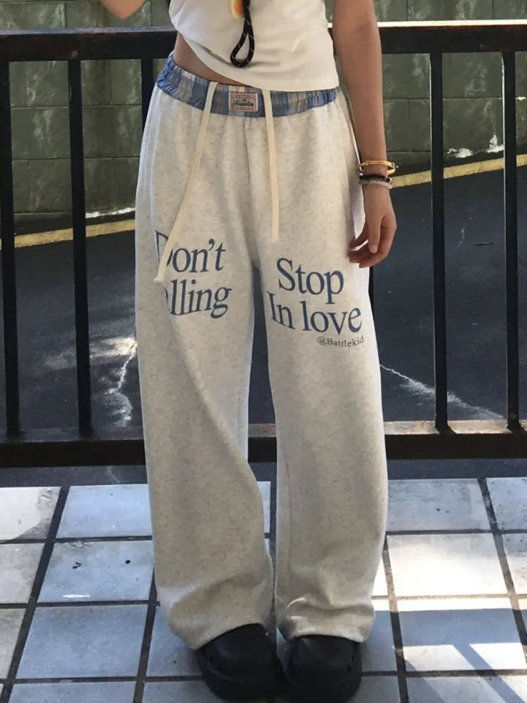 Person wearing gray sweatpants with text on a tiled floor.