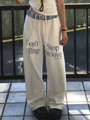 Person wearing gray sweatpants with text on a tiled floor.