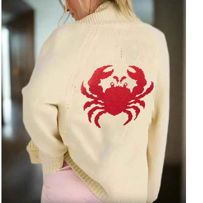 Beige sweater with a red crab design on the back, worn by a person.