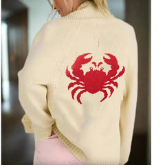 Beige sweater with a red crab design on the back, worn by a person.