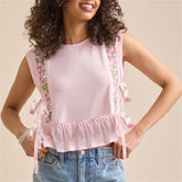 Woman wearing a pink sleeveless top with floral straps against a beige background