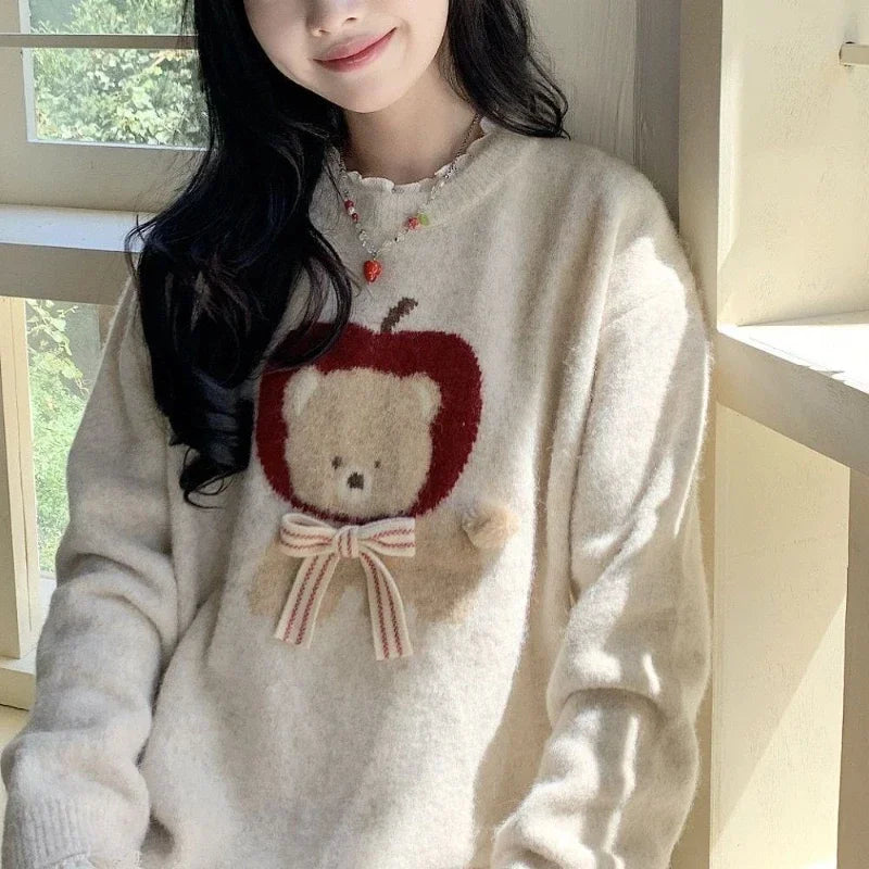 Person wearing a beige sweater with a teddy bear design