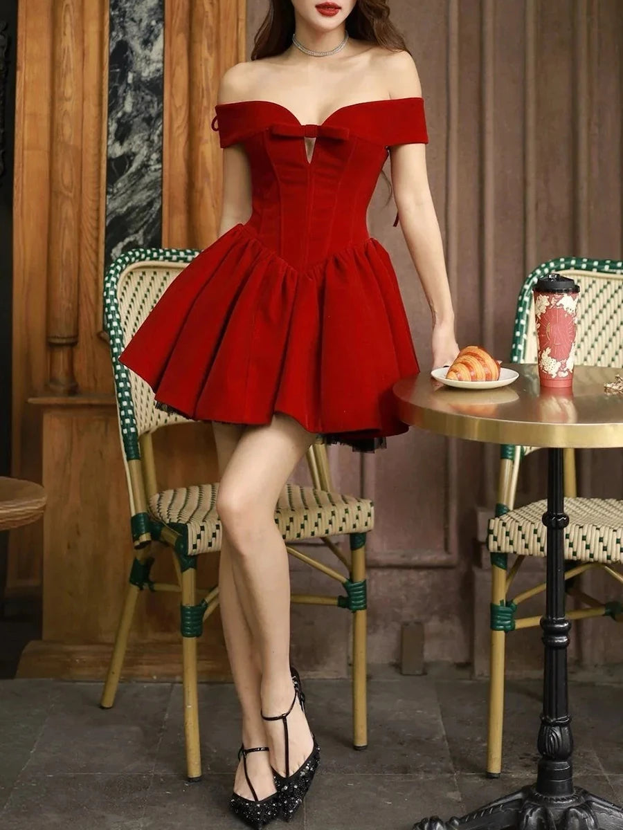 Woman in a red off-shoulder dress standing in a cafe setting.