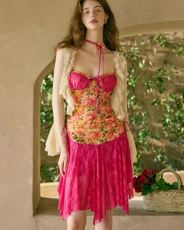 Woman wearing a floral top and pink skirt with a beige cardigan in an outdoor setting.