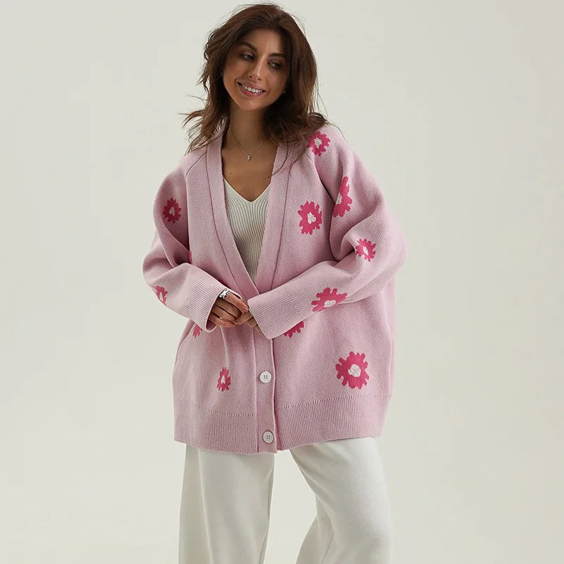Woman wearing a pink cardigan with floral patterns on a plain background