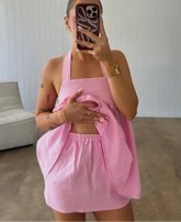 Person wearing a pink outfit taking a mirror selfie in a room with a couch.