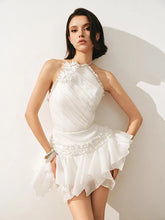 Woman wearing a white dress with floral details against a plain background