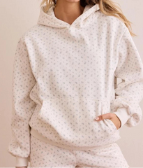 White patterned hoodie worn by a person on a beige background