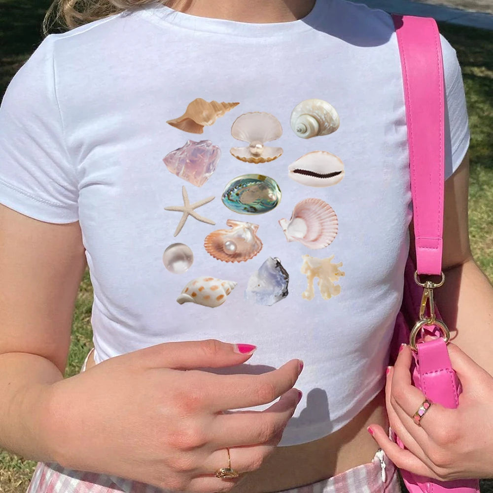 Person wearing a white t-shirt with shell designs outdoors