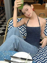 Woman in a blue dress sitting at a table with a drink in a cafe.
