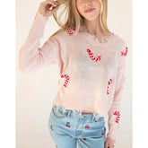 Person wearing a light pink sweater with red candy cane patterns and light blue jeans with red cherry patterns.