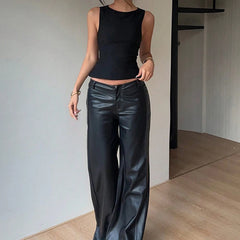 Person wearing a black sleeveless top and black leather pants in an indoor setting.