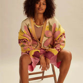 Woman wearing a colorful floral-patterned cardigan sitting on a chair.