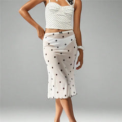 Woman wearing a white polka dot top and skirt on a gray background