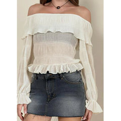 White off-shoulder blouse with ruffled details worn over a denim skirt.