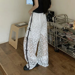 Person wearing white lace pants with black accents in a room.