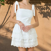 White lace dress worn by a person against a beige wall.