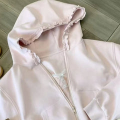Light pink hoodie with ruffle details on a wooden floor
