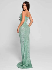 Woman wearing a sparkly green evening gown on a plain background
