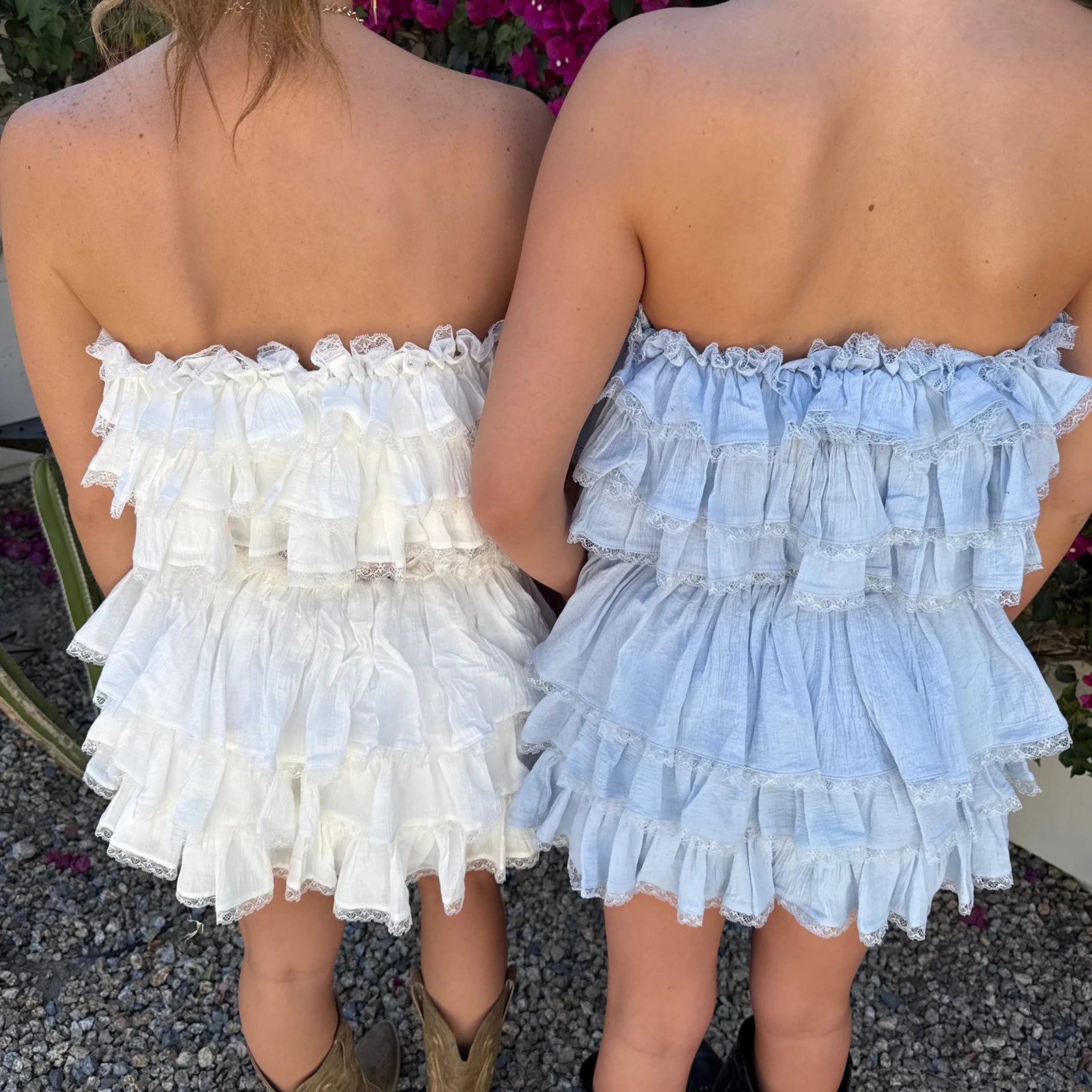 Two people wearing strapless, ruffled dresses in white and light blue.