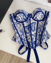 Blue and white patterned corset on a white surface with a black box in the background.
