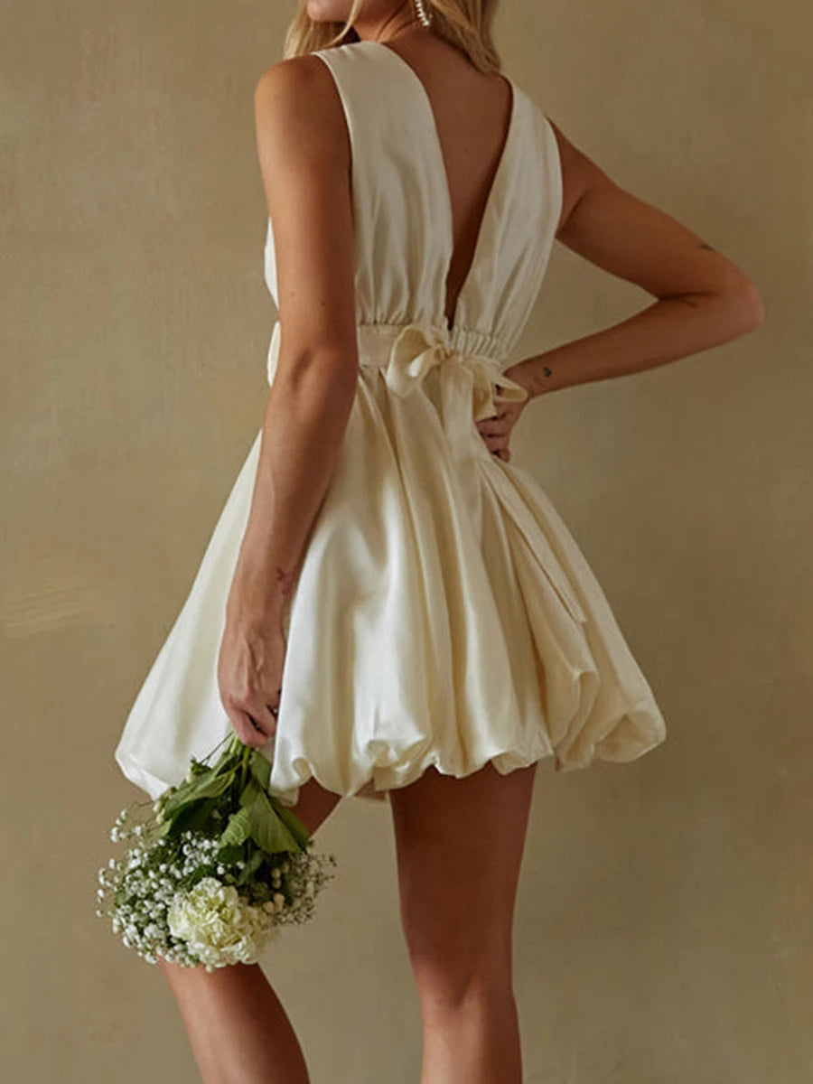 Woman wearing a white dress holding flowers- back view