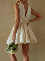Woman wearing a white dress holding flowers- back view