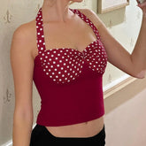 Red polka dot top worn by a person, with a neutral background