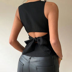 Black sleeveless top with cutout design and bow detail worn by a person on a plain background