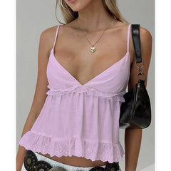 Woman wearing a light purple lace-trimmed top with a plain background