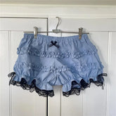Blue ruffled shorts with black lace trim hanging on a rack against a white paneled wall.