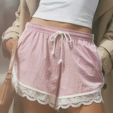 Pink shorts with lace trim worn by a person, blurred background