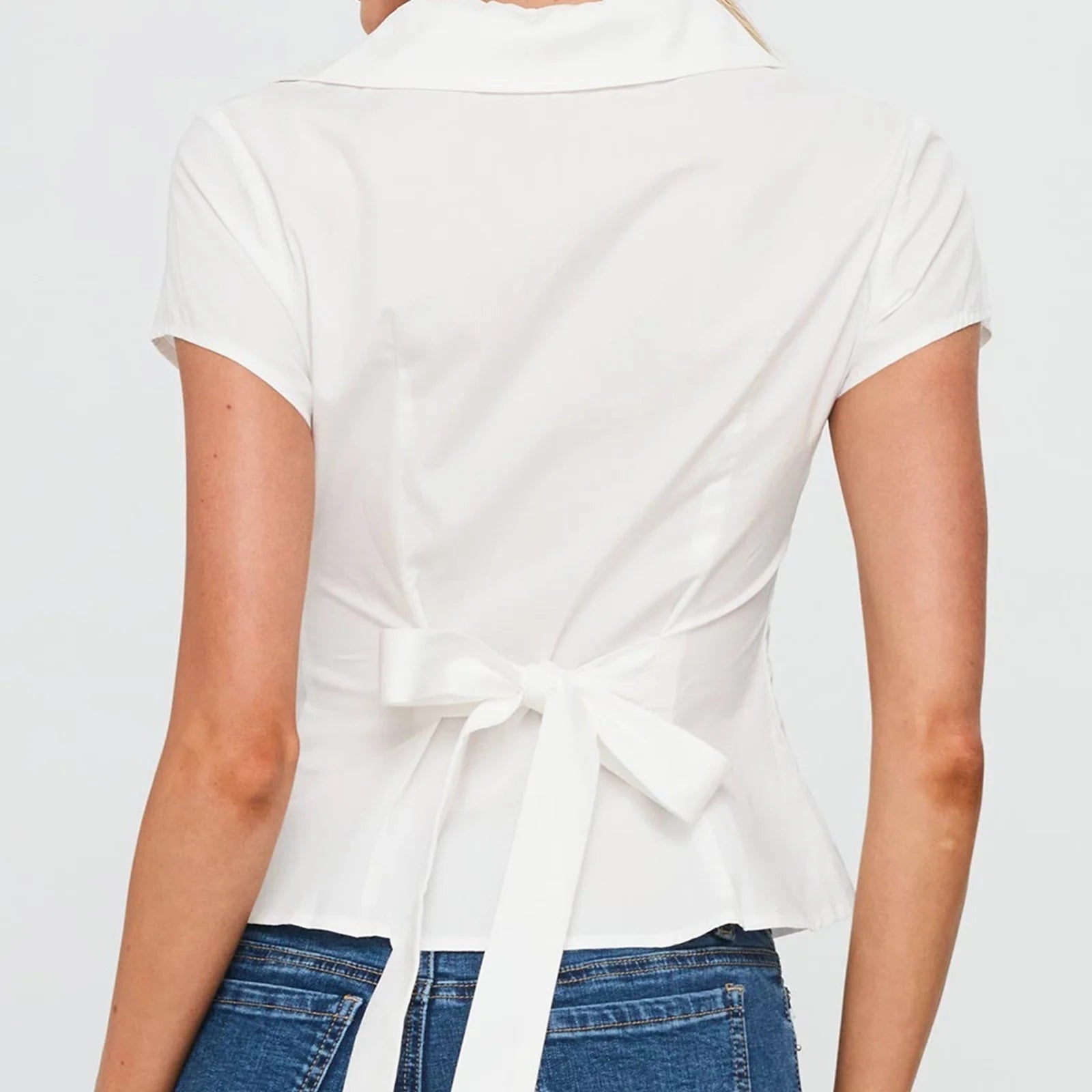 White top with a tie detail worn by a person- belted
