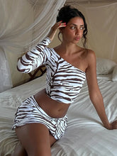 Woman wearing a zebra print outfit sitting on a bed.