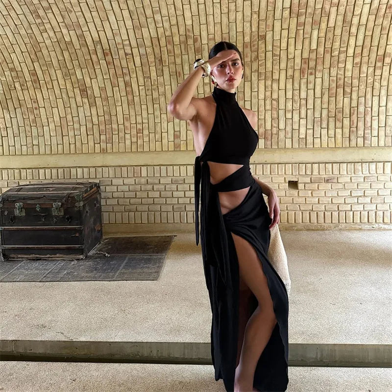 Woman in a black dress posing in a room with a textured wall and wooden chest.