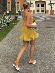 Woman in a yellow dress walking outdoors on a paved path.