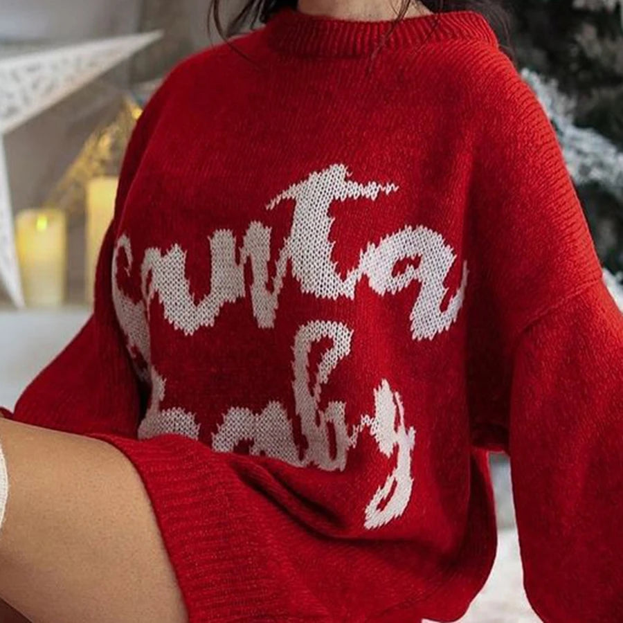 Red sweater with white text and reindeer design worn by a person indoors.