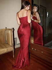 Woman in a red evening gown standing in front of a mirror in an elegant room.