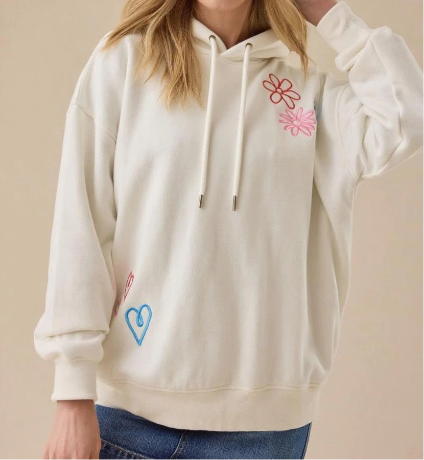 White hoodie with floral designs on a beige background