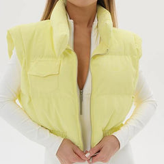 Person wearing a light yellow puffer vest over a white shirt