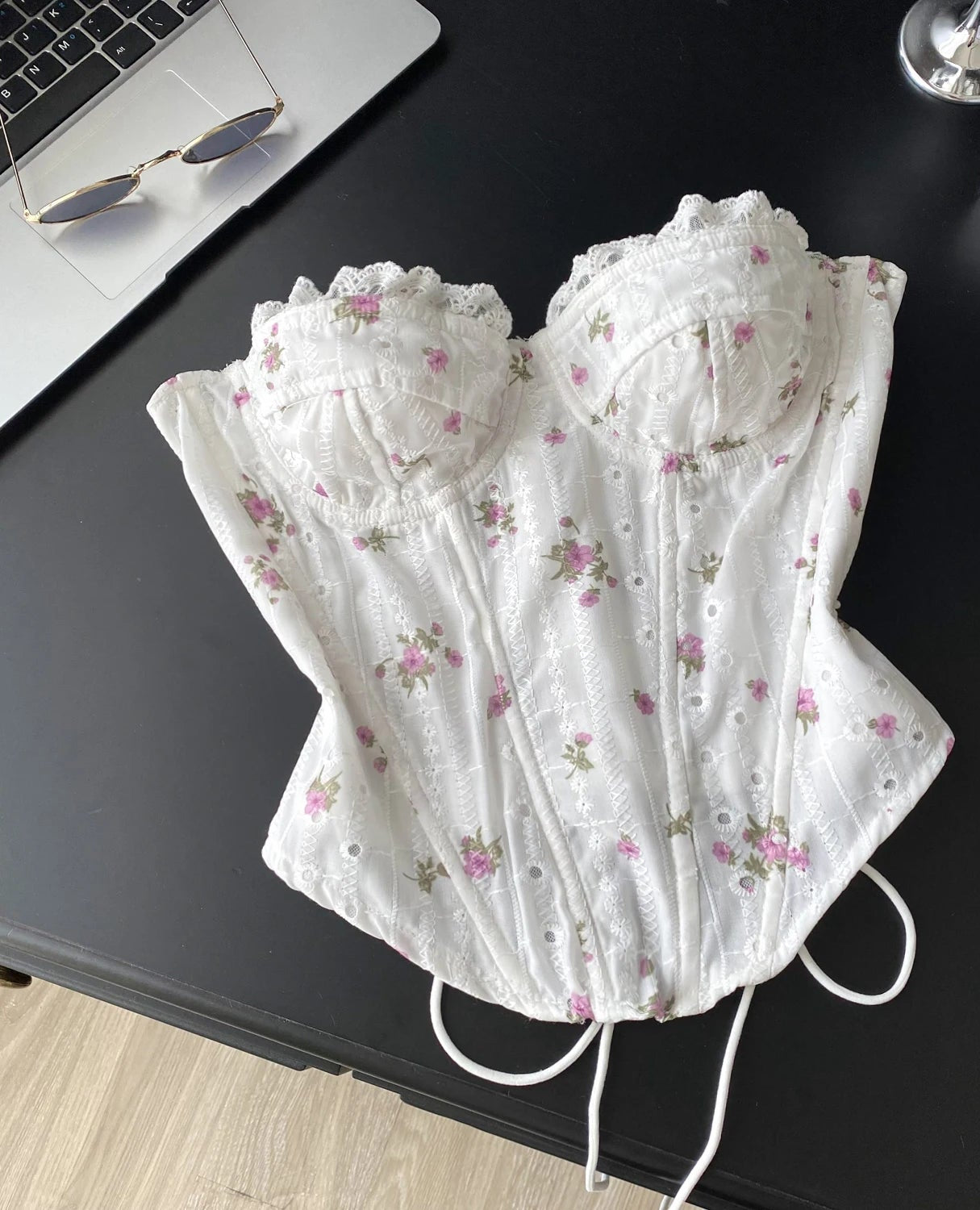 White lace corset with floral patterns on a black surface