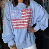 Person wearing a light blue sweatshirt with a red and white checkered pattern on a dark background